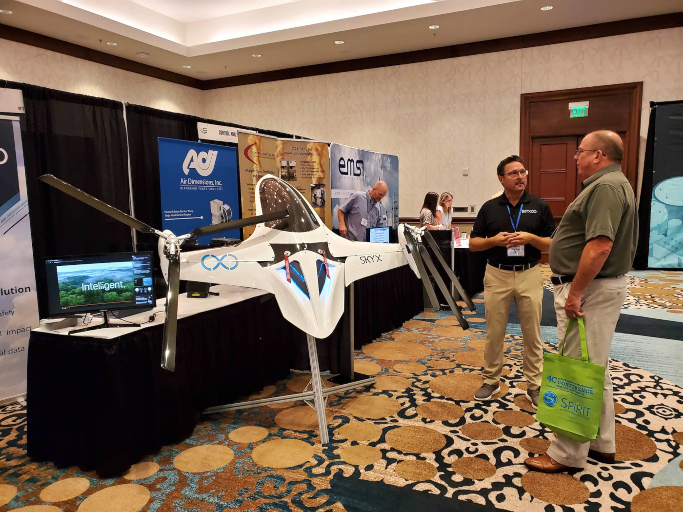 A group of conference attendees networking in front of a vendor booth.