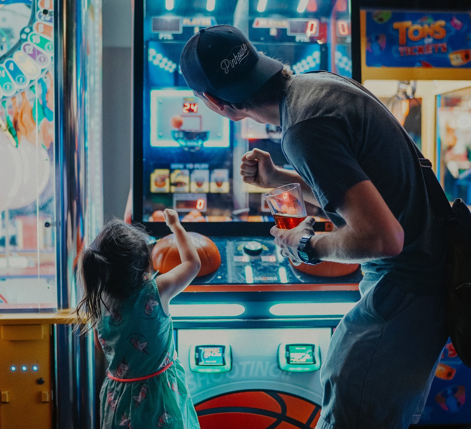 An adult and young child playing an arcade game together.